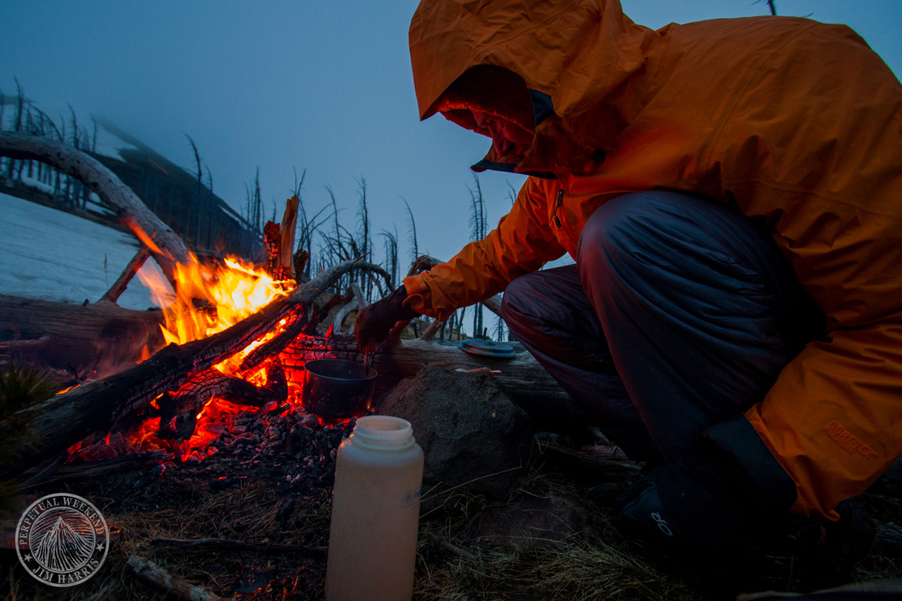 Forrest McCarthy melts water at a ridge line campsite as a storm rolls in. Photo by Jim Harris